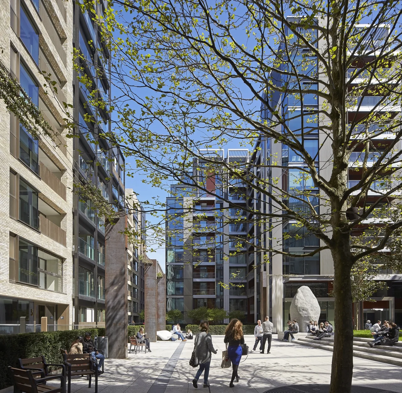 Residents and visitors using a landscaped courtyard between residential buildings