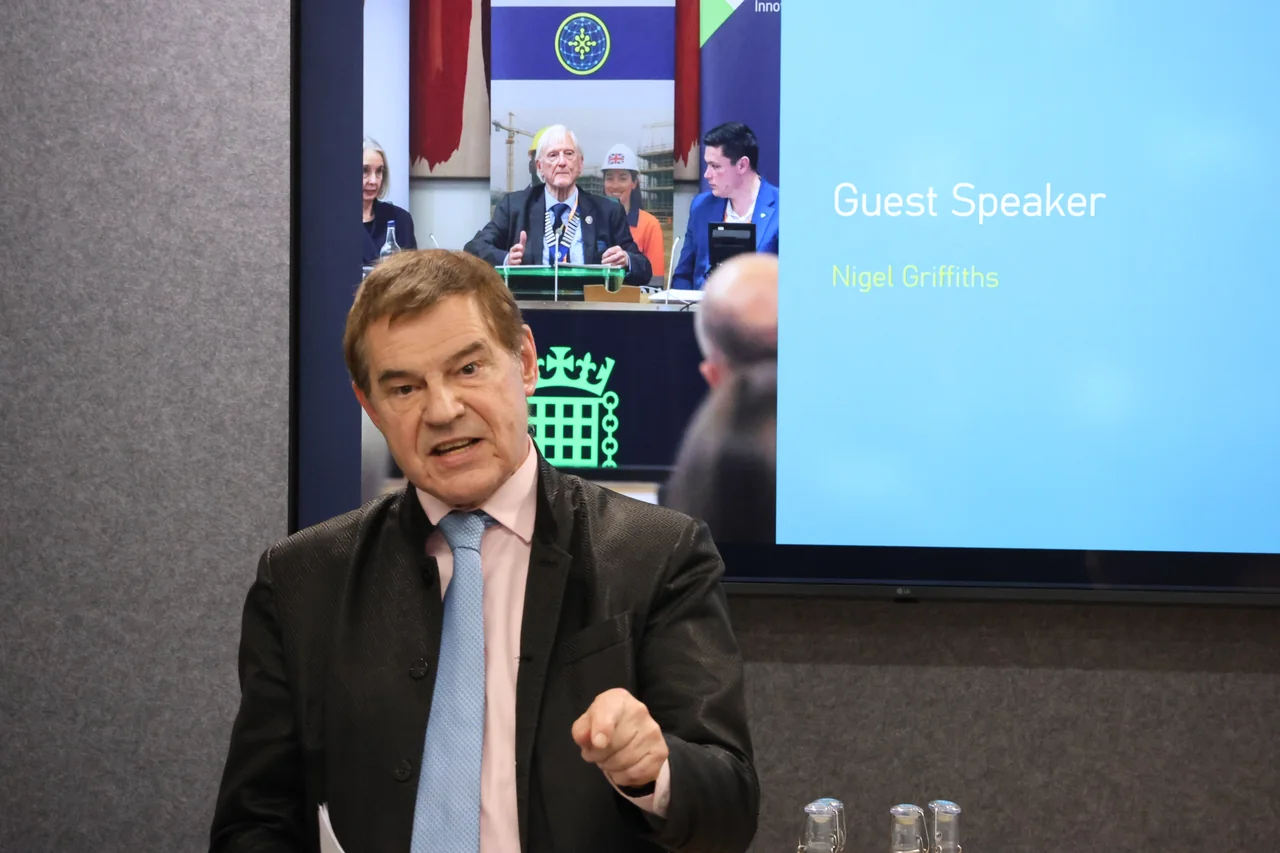 A speaker addressing an industry audience with a parliamentary event on screen